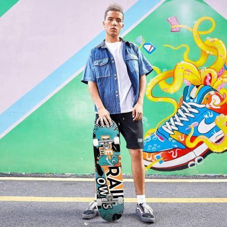 Chico de pie sujetando un skate Hikole Color_10, enfocando su diseño contemporáneo y atractivo