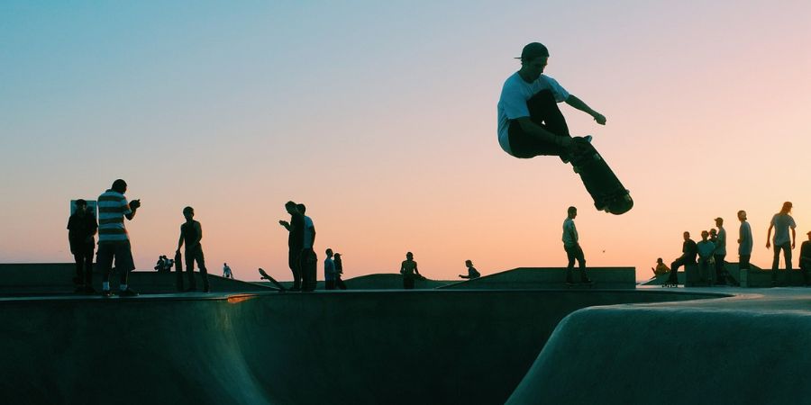 Un skater en acción, capturado en un momento de inspiración, haciendo un truco difícil en el skatepark, con un atardecer urbano, evocando un sentido de logro y la belleza del skateboarding.